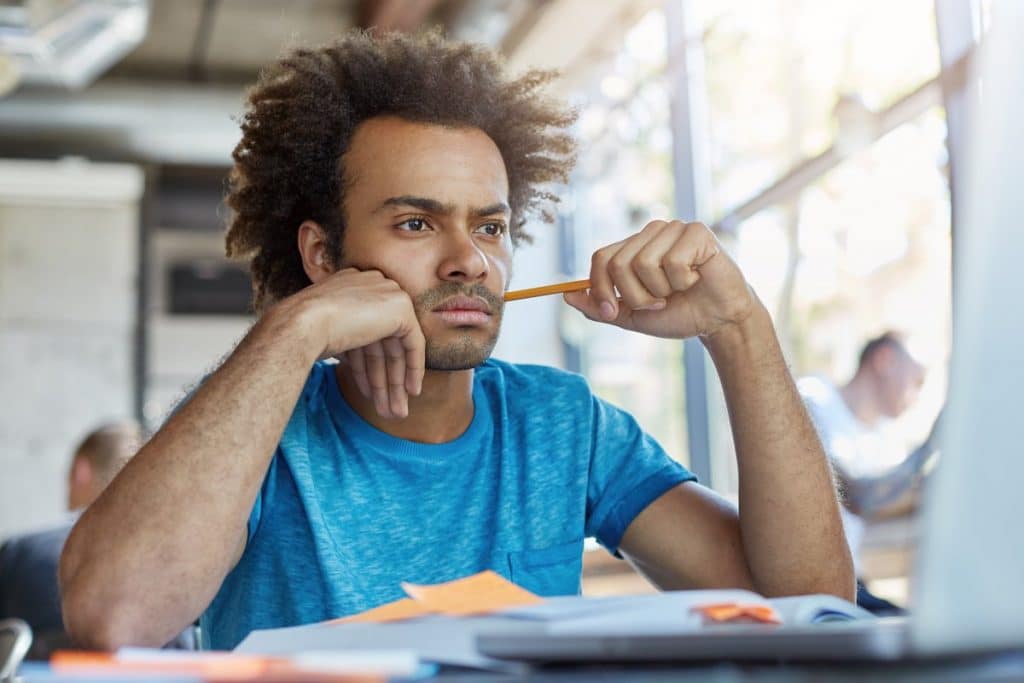 Hombre estudiando con rostro pensativo y preocupado.